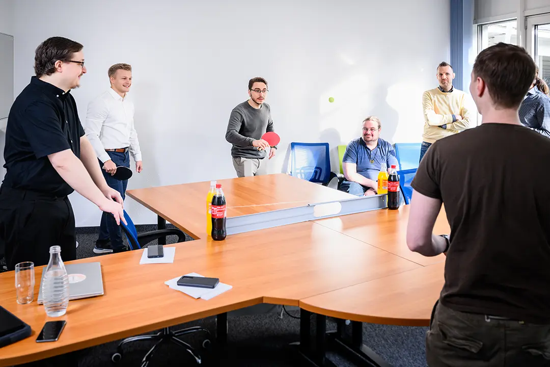 Colleagues playing table tennis in a meeting room.